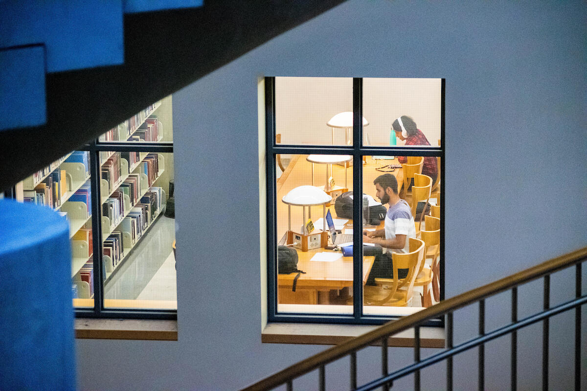 view through a window of students studying in a library